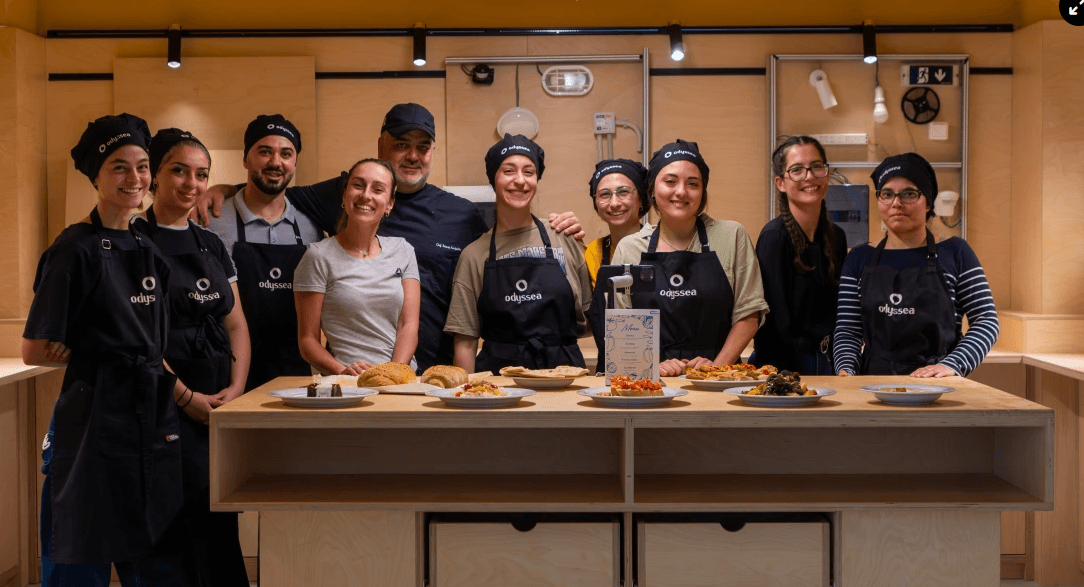 Η ομάδα της κουζίνας GoodBite της Odyssea πίσω από πάγκο με μεσογειακά πιάτα
